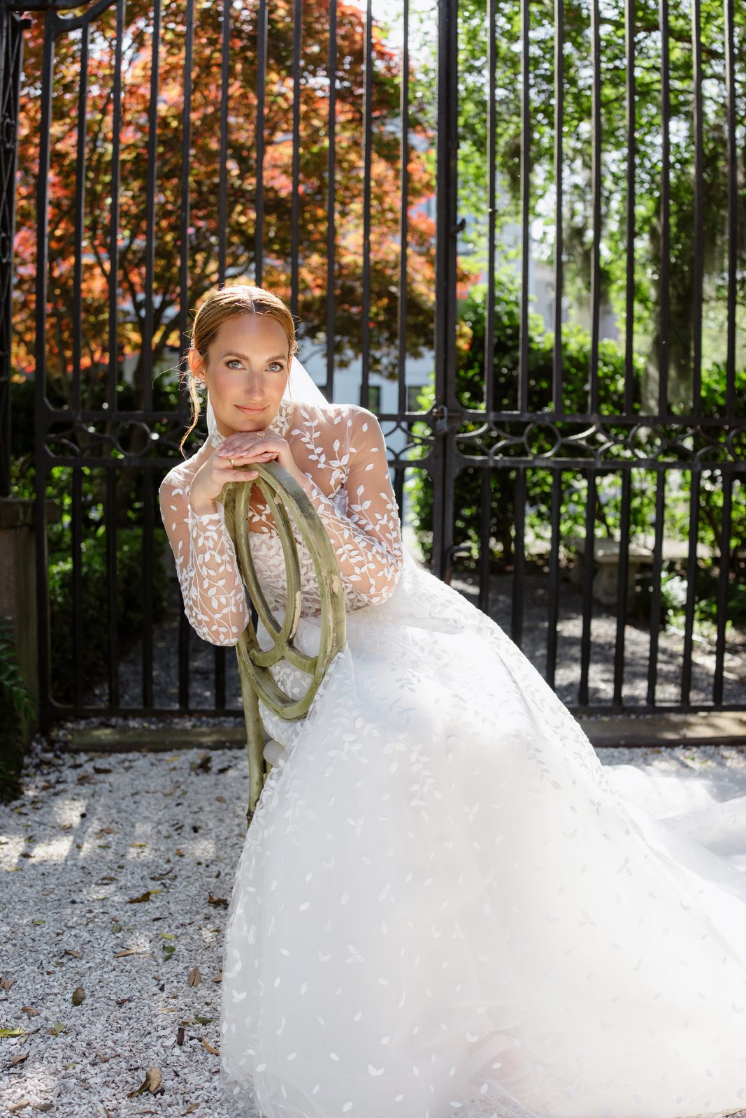 A bride in a leaf-embroidered gown by a wrought-iron gate