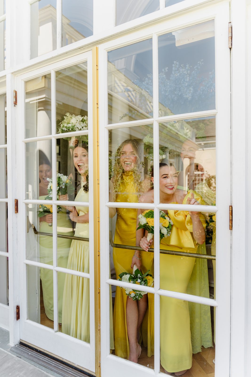 Bridesmaids in yellow framed by French doors